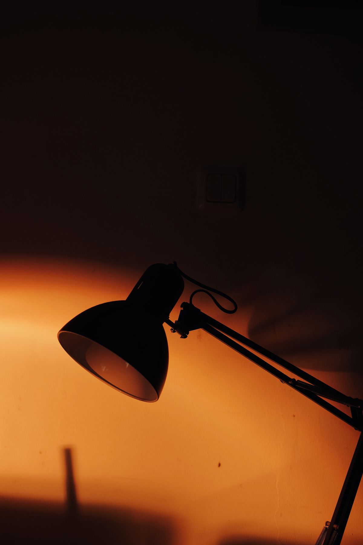 En skrivbordslampa som lyser upp ett mörkt, tomt rum