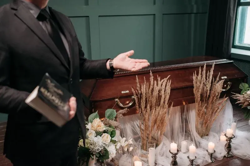En kista omgiven av blommor och tända ljus