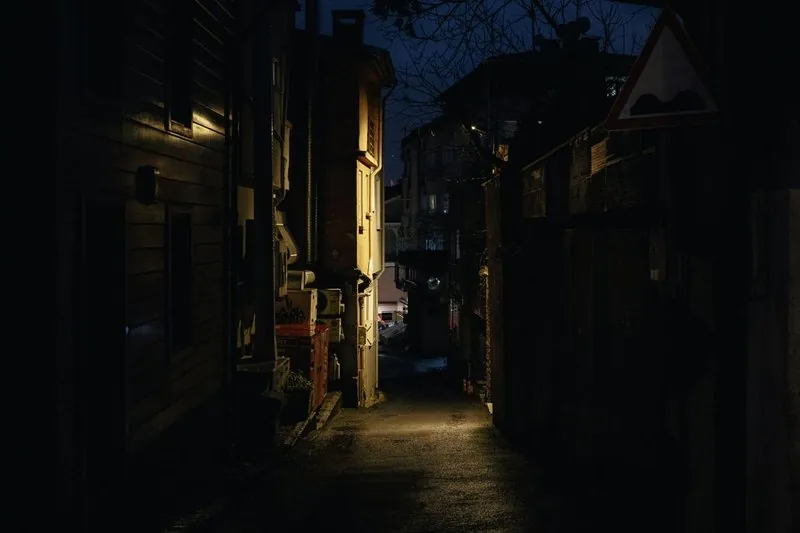 En mörk gränd mellan hus med en ensam lykta