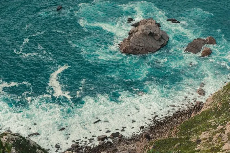 Blicken faller rakt ner för en brant klippa mot havet
