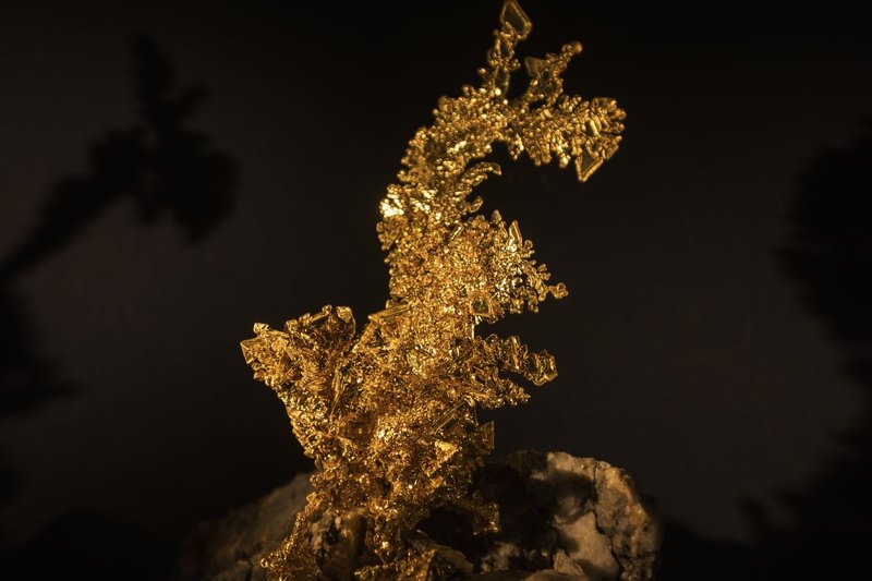 En klump naturligt guld som fångar ljuset mot mörk bakgrund