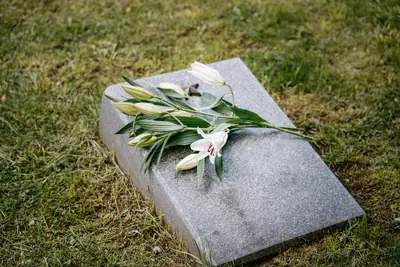 En kista omgiven av blommor och tända ljus