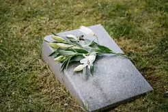 En kista omgiven av blommor och tända ljus