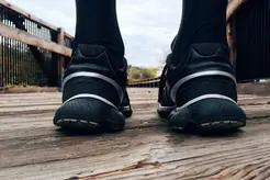 Fötter i svarta sneakers på en träbro