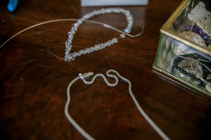 Två tunna halsband på ett mörkt träbord